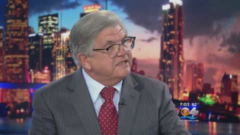 Maximo Alvarez in a dark brown suit and a red tie talking in an interview.